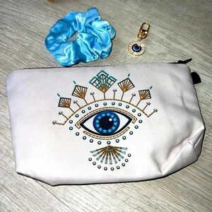 NWOT Evil eye cosmetic pouch with evil eye keychain and blue ponytail.